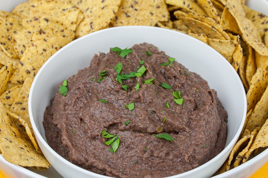 Easy Black Bean Dip - dip in a bowl garnished with cilantro surrounded by tortilla chips