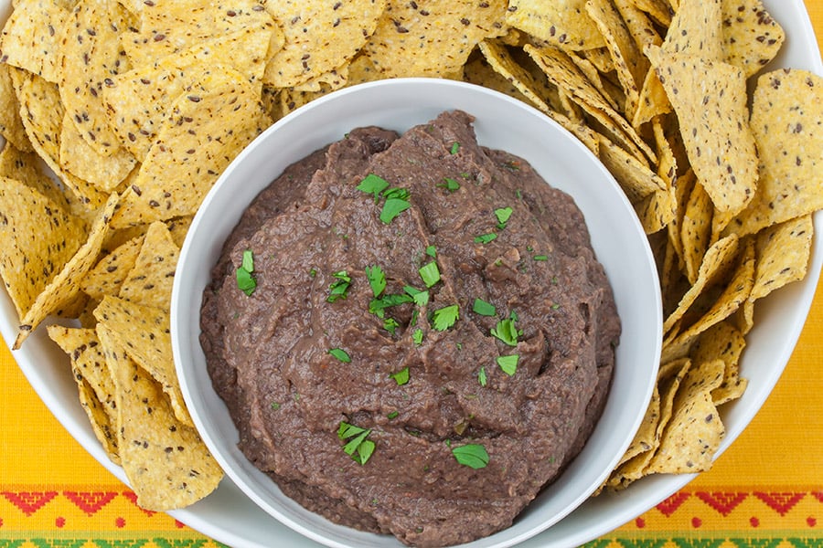 Easy Black Bean Dip - dip in a bowl garnished with cilantro surrounded by tortilla chips