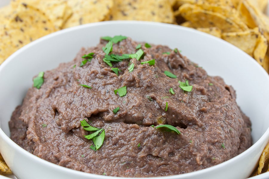 Easy Black Bean Dip - dip in a bowl garnished with cilantro surrounded by tortilla chips
