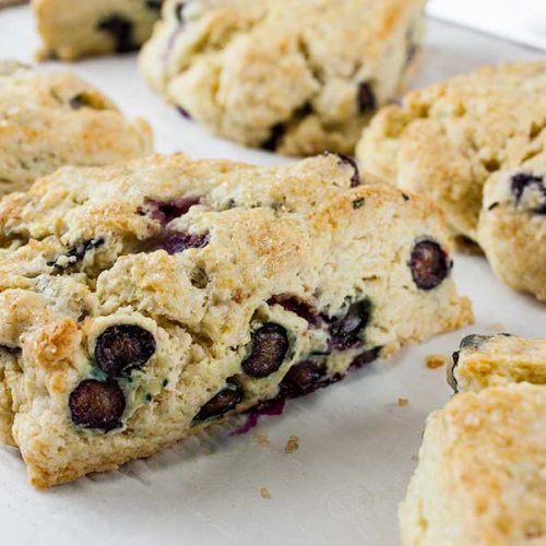 Blueberry Scones - Light, tender, slightly sweet and tangy! This blueberry scone recipe rivals any bakery scone you've ever eaten. Buttery rich and popping with sweet and tangy blueberries!