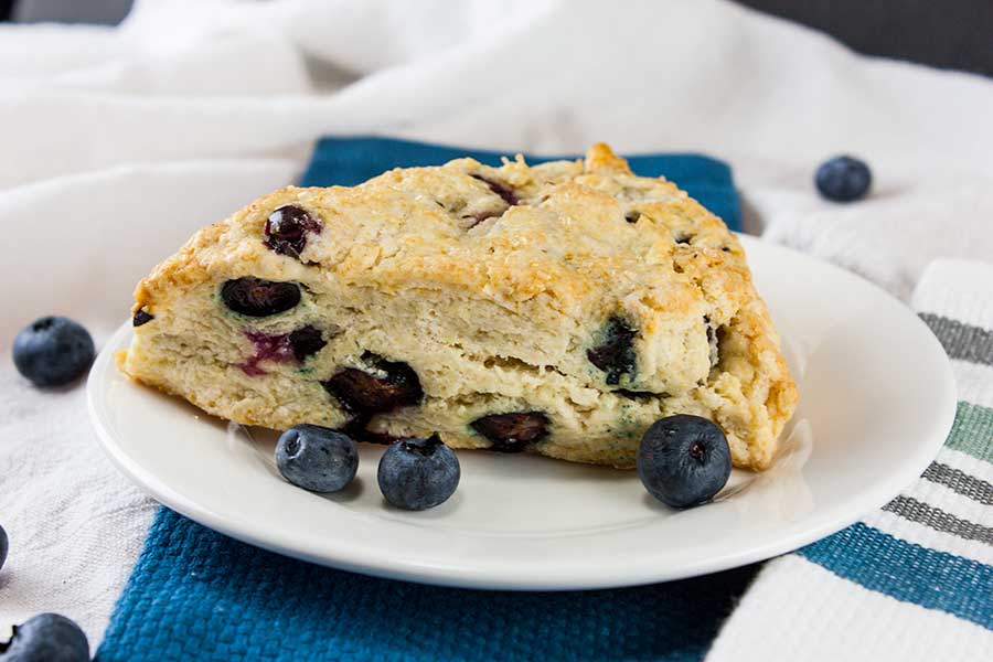Blueberry Scone on a white plate with blue cloth napkin.