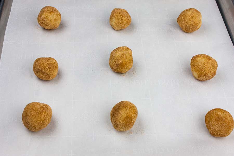 Snickerdoodle dough balls formed on a baking sheet.
