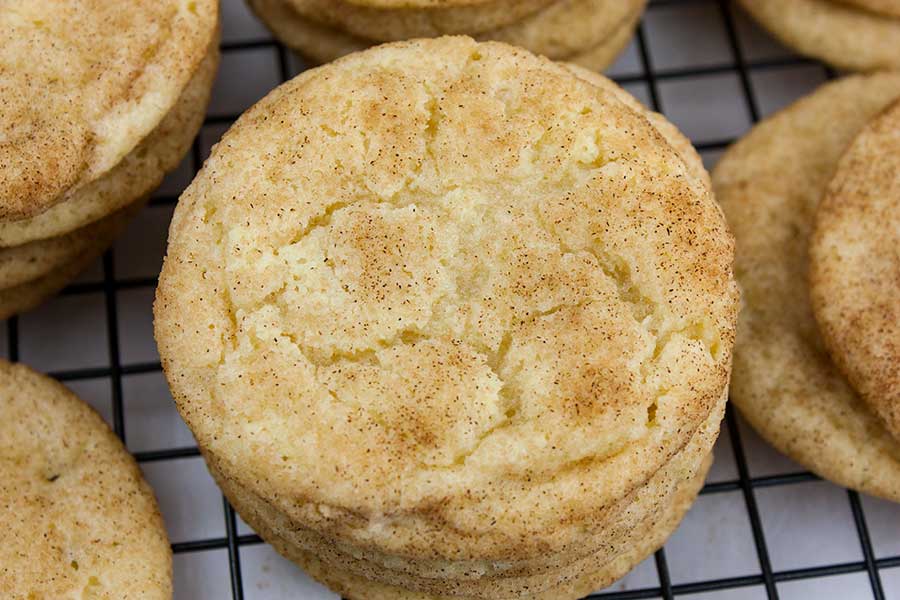 The Best Chewy Snickerdoodle Cookies - baked cookies stacked on a wire cooling rack