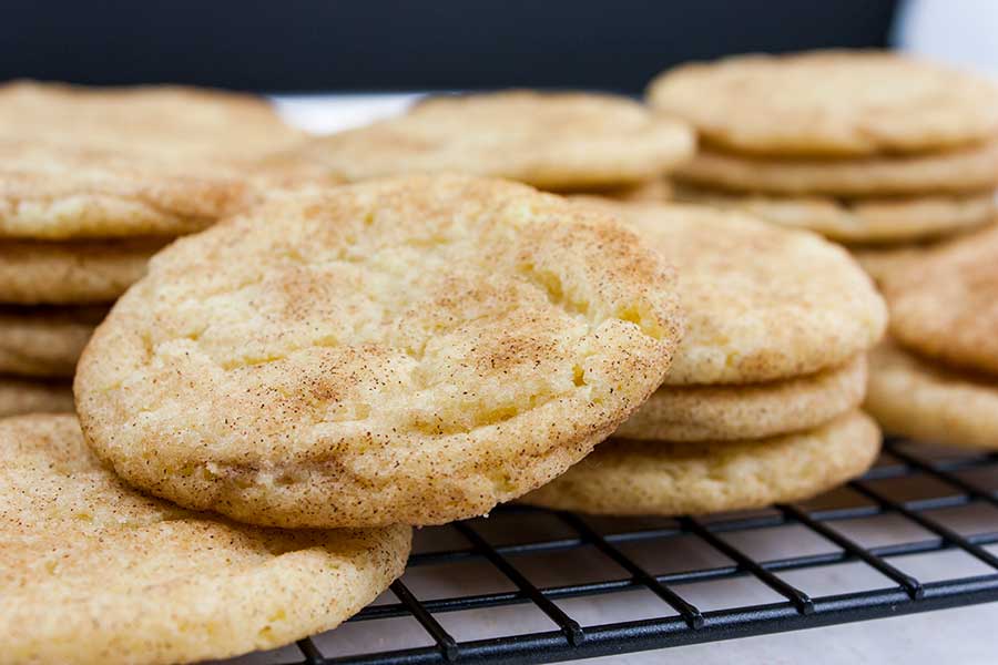 Baked snickerdoodle cookies stacked on a wire cooling rack.