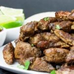 Crispy pork carnitas on a white platter garnished with chopped cilantro.