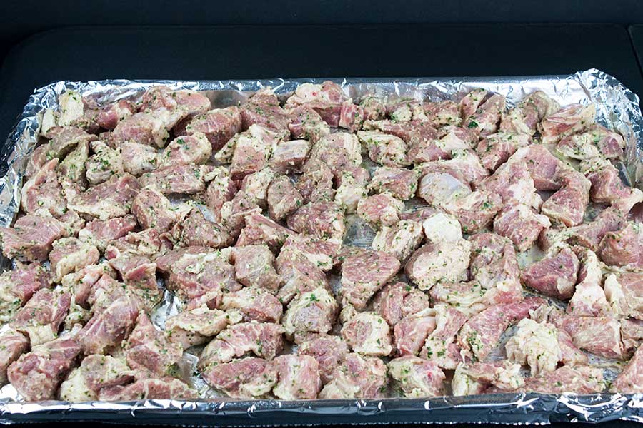 Marinated meat on a foil lined baking sheet.