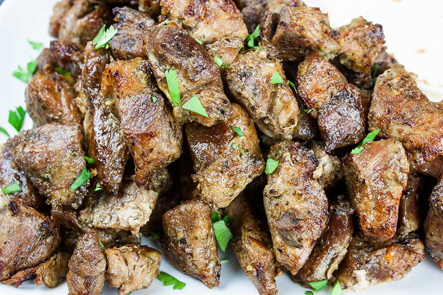 Closeup of the crispy pork carnitas on a white plate garnish with chopped cilantro.