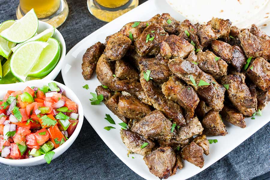 Crispy pork carnitas on a white platter garnished with chopped cilantro.