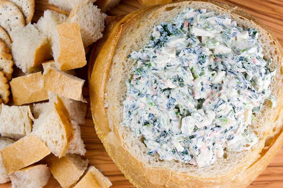 Easy Spinach Dip inside a bread bowl with cubed bread next to it.