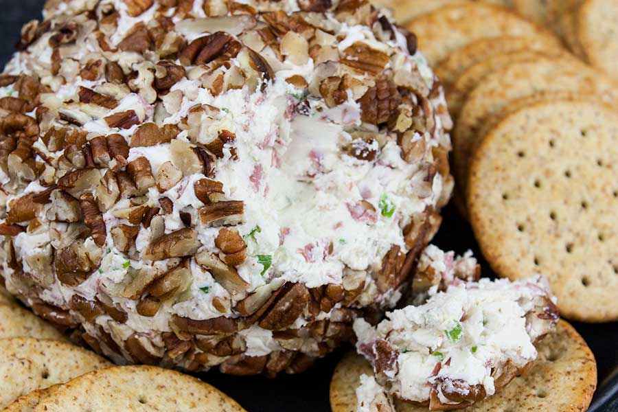 Pecan crusted cheese ball surrounded in crackers.