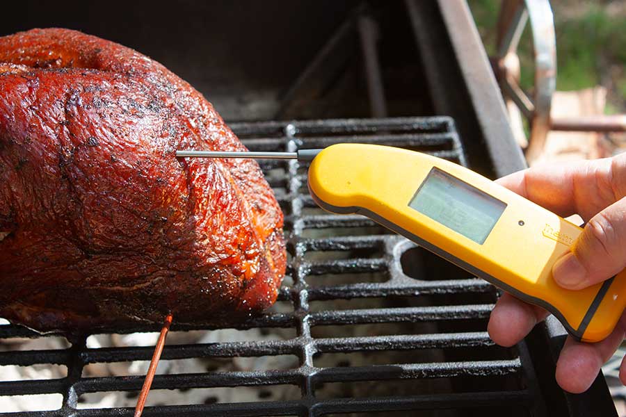 thermometer inserted into the turkey breast on the smoker.