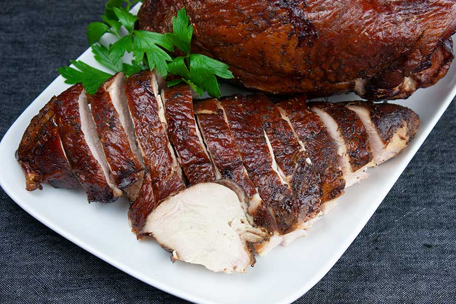 Smoked turkey breast on a white serving platter.