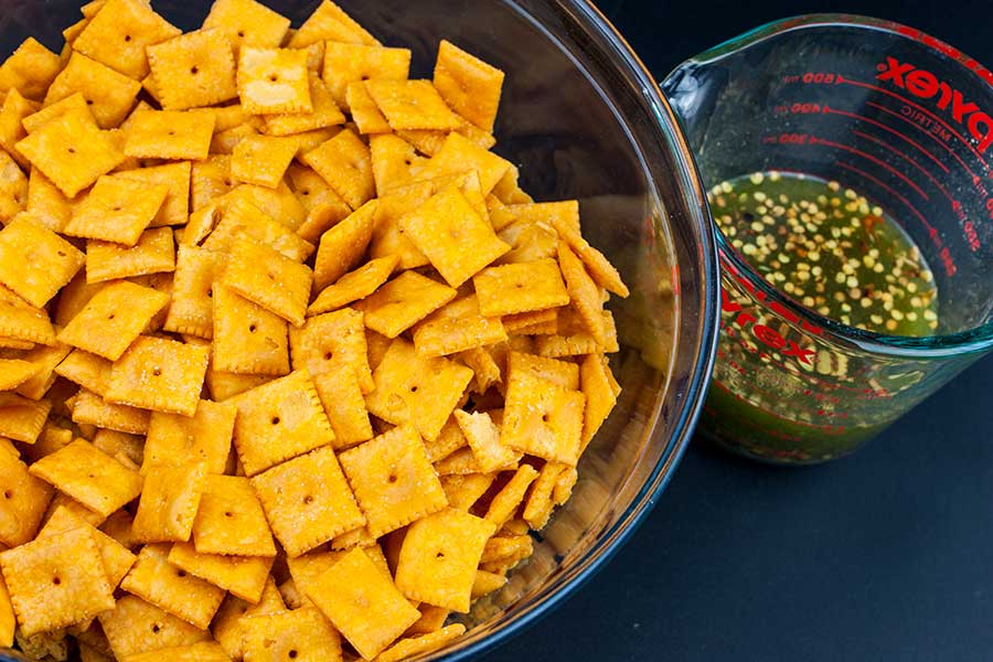 Firecracker Cheez-Itz - crackers in a large glass bowl with seasoning mixture in a glass measuring cup next to it