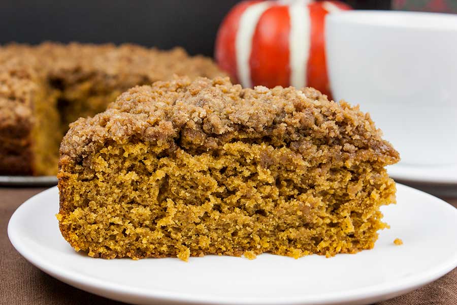 A slice of pumpkin coffee cake with streusel topping on a white plate.