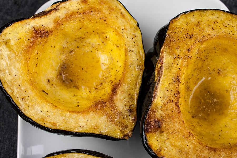 Closeup of roasted acorn squash on a white plate.