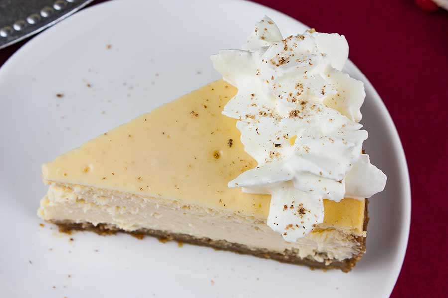 A slice of eggnog cheesecake on a white plate.