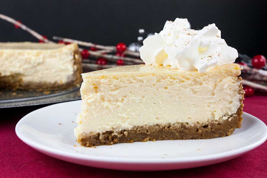 Eggnog Cheesecake with Gingersnap Crust - slice of cheesecake on a white plate