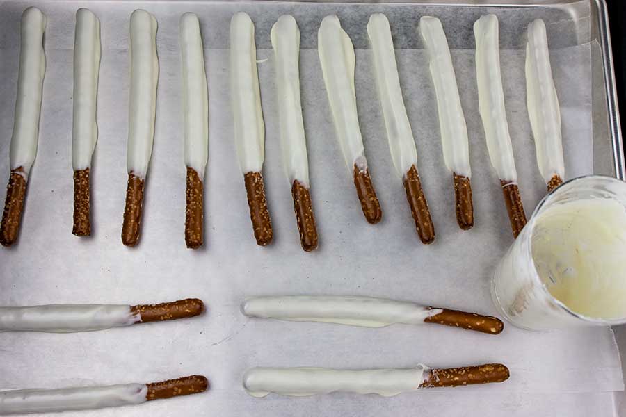 White Chocolate Covered Pretzel Rods on a parchment paper lined baking sheet.