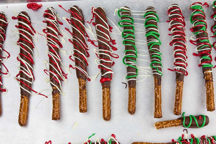 Chocolate Covered Pretzel Rods - pretzel rods dipped in chocolate and drizzled with red, white, and green chocolate placed on parchment paper