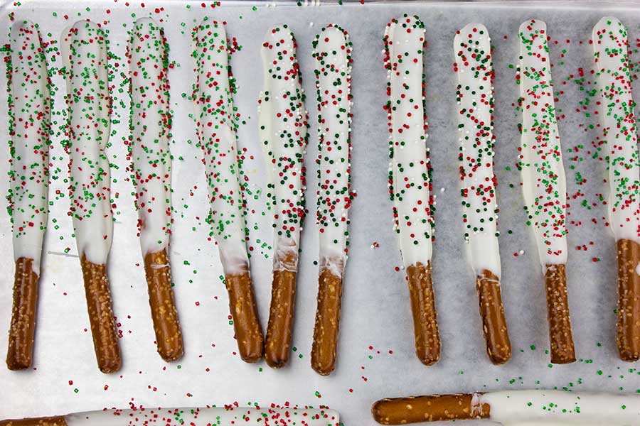 White Chocolate Covered Pretzel Rods on a parchment lined baking sheet.