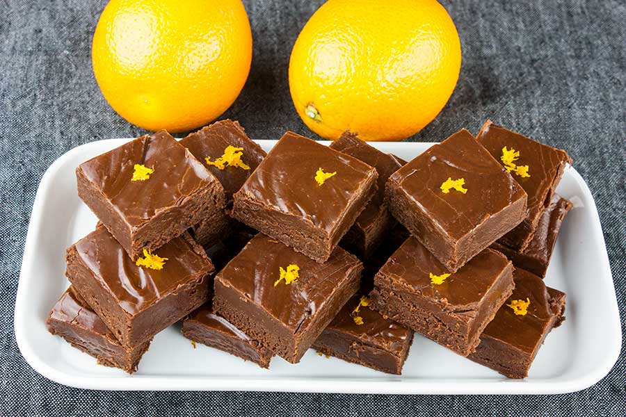Chocolate Orange Fudge cut in squares placed on a white plate and garnished with orange zest.