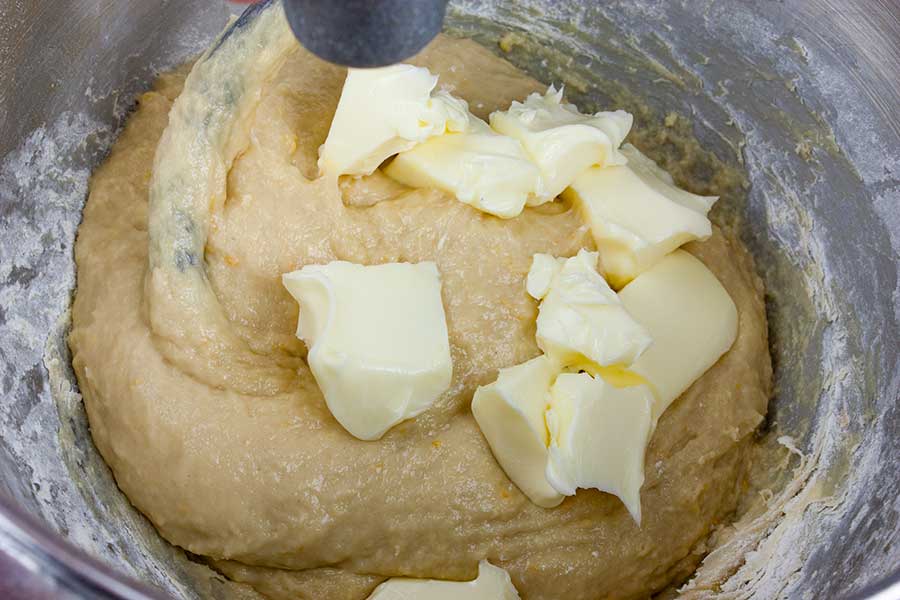 Butter added to the panettone dough in a metal mixing bowl.