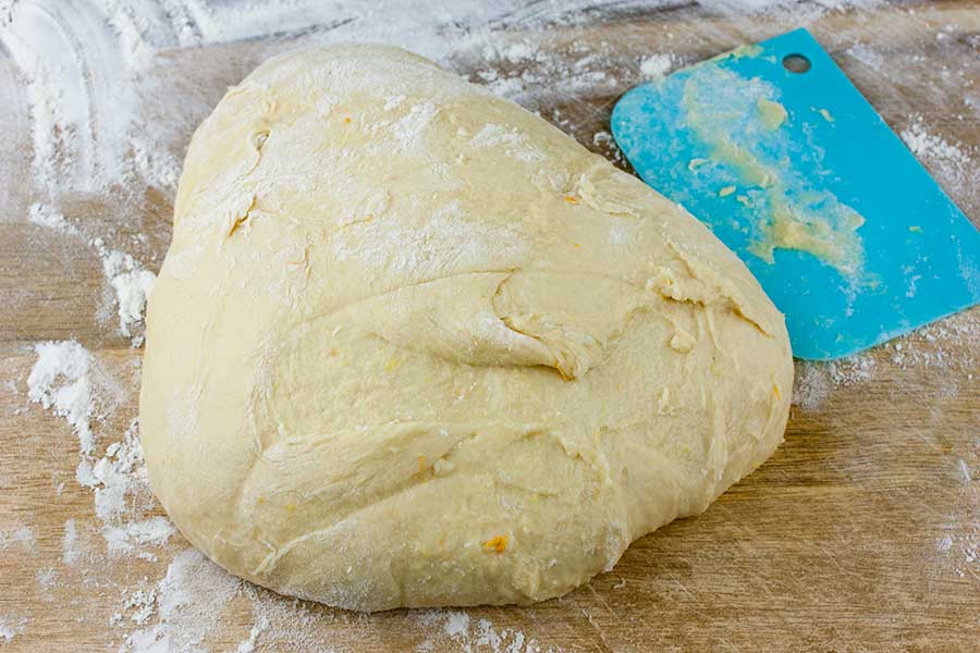 Panettone dough on a wooden board with flour.