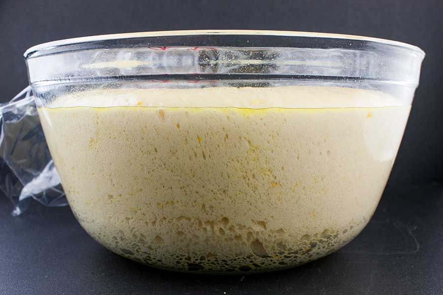 Risen panettone dough in a glass bowl.