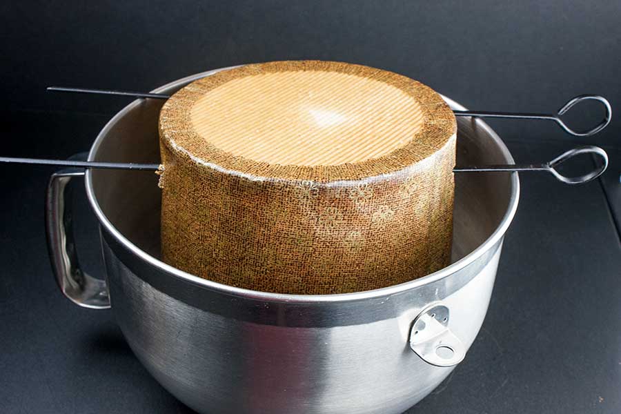 The baked panettone hung upside down in a large deep metal bowl.