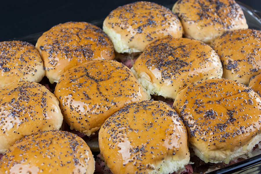 pastrami and swiss cheese sliders covered in butter and poppy seeds
