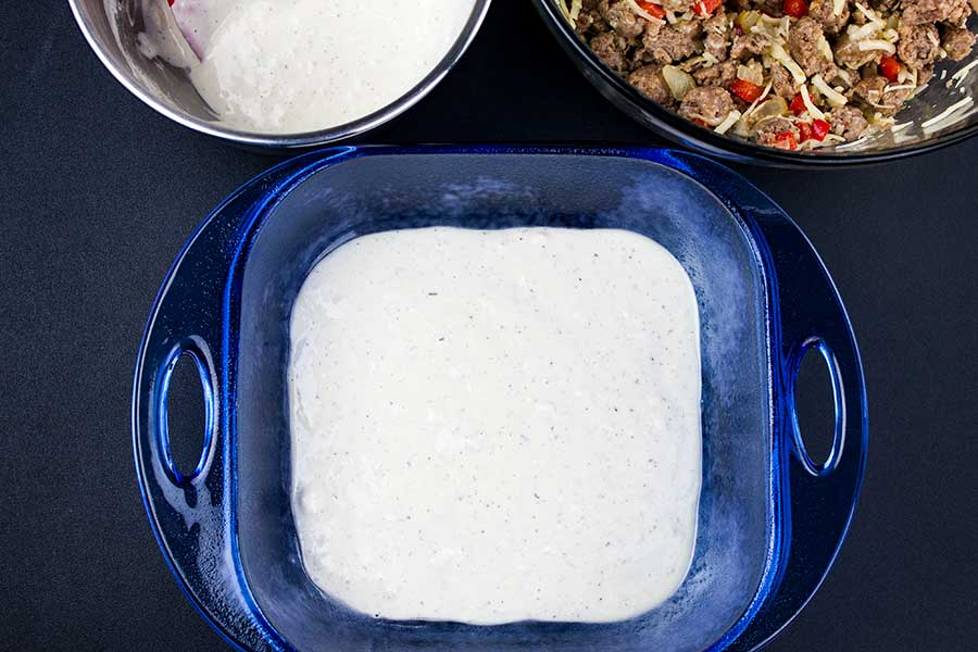 Sausage Breakfast Cake Recipe - first layer of batter in the bottom of a blue glass pan