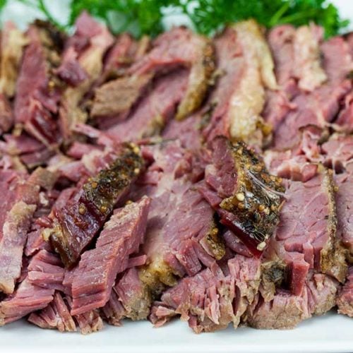 Slow cooker corned beef on a platter garnished with parsley.