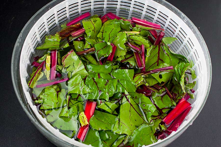 beet greens in a salad spinner filled with water