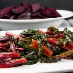 Ninja Foodi fresh beet greens on a white platter with fresh beets in the background.