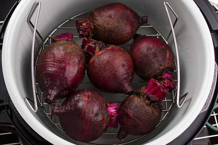 Raw beets with greens removed on the lower rack in the Ninja Foodi pot.