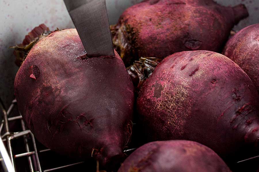 Cooked beets being tested with the tip of a knife for tenderness.