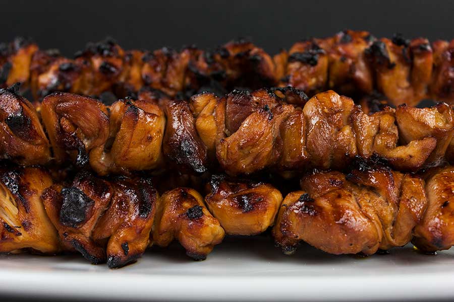 grilled Filipino chicken kebabs stacked on a white platter