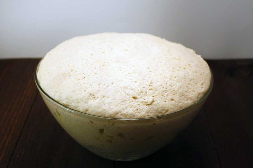 Risen dough in a glass bowl.