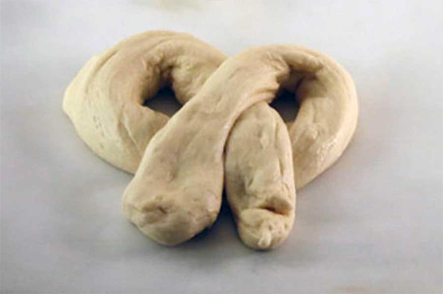 Shaped pretzel dough on parchment paper.