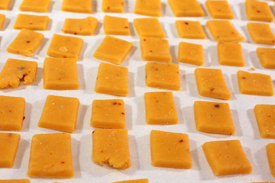Spicy Cheese Crackers cut into squares on a parchment lined baking sheet.