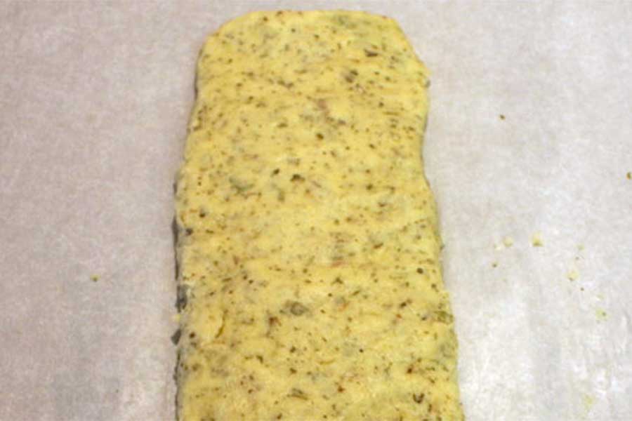 Biscotti dough formed into a log on parchment paper.