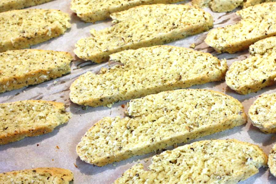 Savory Herb and Cheese Biscotti sliced on a parchment paper lined baking sheet.