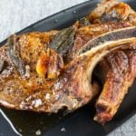 Thick cut bone in pork chops on a black plate.