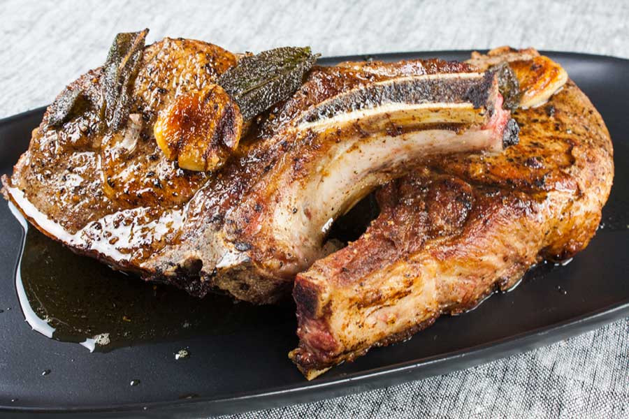 Cooked bone in pork chops on a black plate