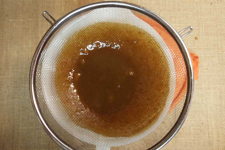 Pumpkin spice syrup in a strainer.