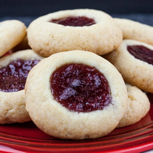 Thumbprint cookies stacked on a red plate.