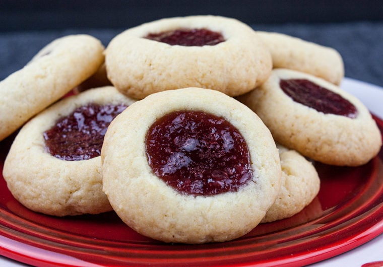 A soft, delicate, slightly crisp cookie base filled with sweet, tangy red raspberry jam! This easy Red Raspberry Thumbprint Cookie recipe is a Christmas tradition.