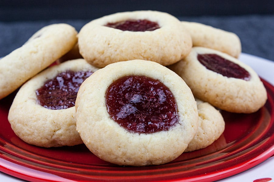 Thumbprint cookies stacked on a red plate.
