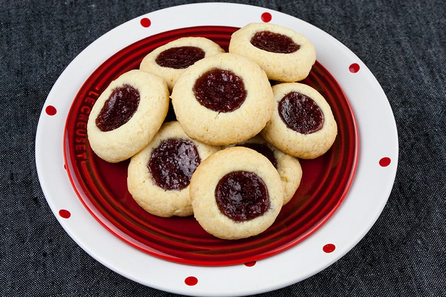 A soft, delicate, slightly crisp cookie base filled with sweet, tangy red raspberry jam! This easy Red Raspberry Thumbprint Cookie recipe is a Christmas tradition.