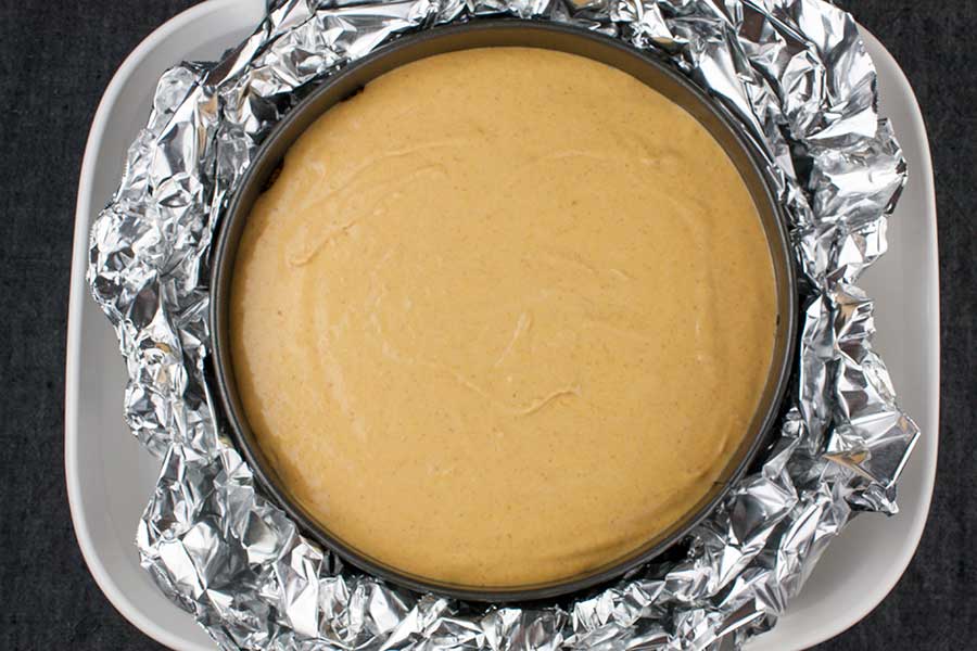 Cheesecake batter in the springform pan inside a water bath pan.